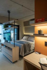 a bedroom with a bed and a desk with a television at Loft Marília City in Marília