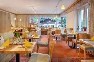 a restaurant with wooden tables and chairs and windows at Pension St.Leonhard in Bad Gastein