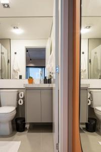 a bathroom with a toilet and two sinks and mirrors at Loft Marília City in Marília