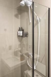 a shower with a shower head and a glass door at Loft Marília City in Marília
