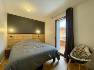 ein Schlafzimmer mit einem Bett und einem Stuhl und einem Fenster in der Unterkunft Homency - Résidence Fermes de l'Alpe C101 in L'Alpe-d'Huez