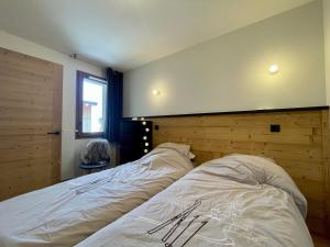 ein Schlafzimmer mit einem Bett mit einem hölzernen Kopfteil in der Unterkunft Homency - Résidence Fermes de l'Alpe C101 in L'Alpe-d'Huez