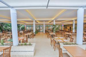 an empty restaurant with wooden tables and chairs at Club Mirabell hotel in Elikesik