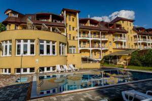ein großes gelbes Gebäude mit einem Schwimmbad davor in der Unterkunft Hotel Venus in Zalakaros