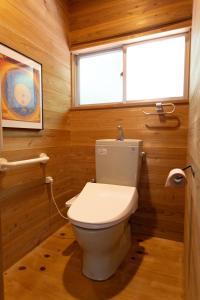 a bathroom with a toilet in a room with wooden walls at Halo in Oshima