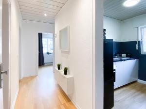 a kitchen and living room with white walls and wood floors at ALFA Apartment Esslingen City Altstadt nahe Stuttgart Messe I 3 Zimmer 4 Betten I Bad I Küche l WIFI & SmartTV I 3BR 4Beds I Bathroom I Kitchen in Esslingen