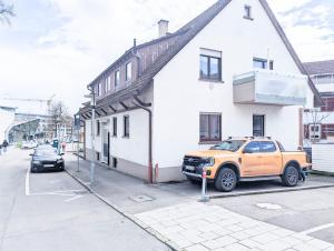 an orange truck parked in front of a white building at ALFA Apartment Esslingen City Altstadt nahe Stuttgart Messe I 3 Zimmer 4 Betten I Bad I Küche l WIFI & SmartTV I 3BR 4Beds I Bathroom I Kitchen in Esslingen