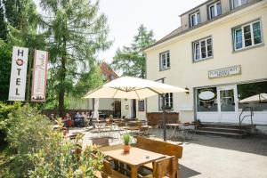 un ristorante con tavoli e ombrelloni di fronte a un edificio di Fliegerhorst a Dresda