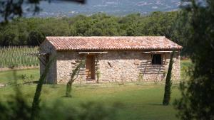 a small stone building in a field with trees at Domaine Pozzo di Mastri in Figari