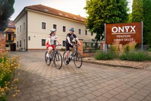 two people riding bikes in front of a building at Penzion Onyx in Lednice