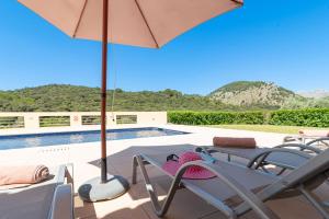 un patio con sillas y una sombrilla junto a la piscina en Villa Malagarba d'Enmig by Sealand Villas, en Pollensa