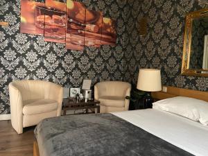 a bedroom with two chairs and a bed and a mirror at Chambre année 70 in Brussels