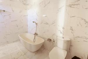 a white bathroom with a toilet and a sink at Olivia Guest House Canggu in Canggu +18 photos