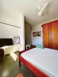 a bedroom with a large bed and a flat screen tv at Suíte Ita no Bairro Itaguá!!! in Ubatuba
