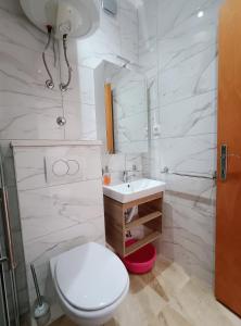 a white bathroom with a toilet and a sink at Apartments Anita Hure in Hvar