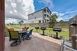 um pátio com cadeiras, uma mesa e comodidades para churrascos em Harbor Place Condos em Gulf Shores