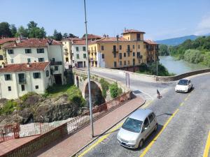 a street with cars driving on a road next to a river at Gusterhouse Castellazzo in Ivrea