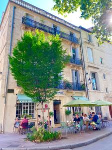 a group of people sitting at tables in front of a building at Hotel du Palais in Montpellier