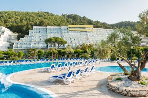拉巴克MASLINICA Mimosa Lido Palace Hotel的一个带游泳池和椅子的度假胜地和一座建筑