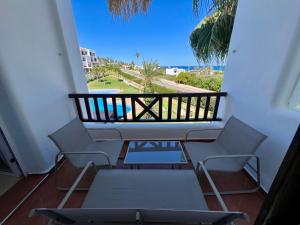 a balcony with chairs and a table and a view of the ocean at Blue Pearl Apartment in Cabo Negro
