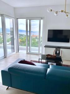 a blue couch in a living room with windows at 4Star Seaview Penthouse Krk in Krk