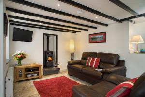 a living room with a leather couch and a fireplace at Bern Cottage Tresaith in Tresaith