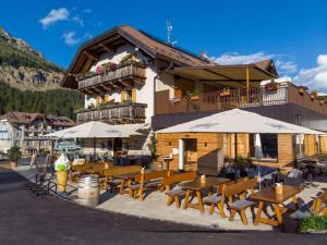 a restaurant with tables and umbrellas in front of a building at Bar-Restaurant-Pizzeria Antermont B&B in Carezza al Lago