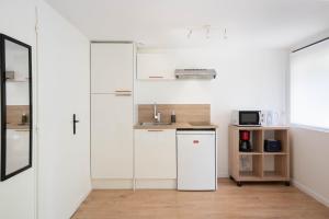 a kitchen with white walls and a white refrigerator at Les Studios De Honfleur in Honfleur