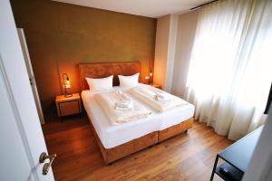 een slaapkamer met een bed met witte lakens en een raam bij Winzerhaus am Kardinalsberg in Bernkastel-Kues