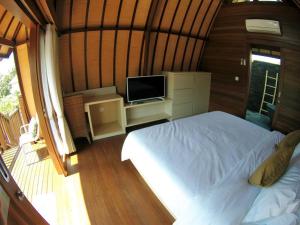 a bedroom with a bed and a flat screen tv at Villa Kenken - 2 Bedrooms villa close to Keramas Surfing Beach in Keramas