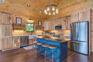 a kitchen with wooden cabinets and a blue island with bar stools at Southern Stars by Stony Brook Cabins in Rocky Grove +46 photos