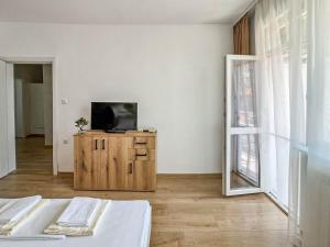 a bedroom with a television on a wooden dresser at Апартамент Tiana in Tsarevo