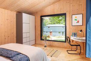 ein Schlafzimmer mit einem Fenster, einem Bett und einem Schreibtisch in der Unterkunft Traumhaus direkt am See mit Dachterrasse, Kamin und Badewanne in Templin + 25 Fotos