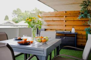 a table with bowls of fruit on a patio at Appartement lumineux proche lac in Mimizan +32 photos