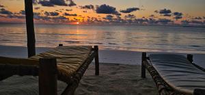 two beds on the beach with a sunset in the background at AVO Boutique Hotel in Dikoni