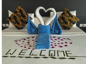 a bed with two towels and a welcome sign on it at AVO Boutique Hotel in Dikoni