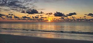 a sunset on the beach with the sun setting at AVO Boutique Hotel in Dikoni
