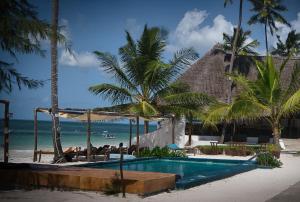 a pool on the beach with palm trees and the ocean at AVO Boutique Hotel in Dikoni