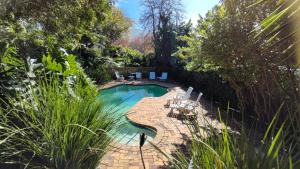 a swimming pool in a yard with chairs around it at Squirrels Nook Cottage Constantia in Cape Town