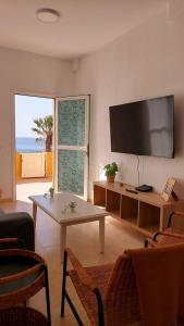 een woonkamer met een tafel en een groot televisiescherm bij La Marea Baja in Puertito de Güímar