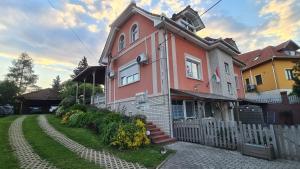 a pink house with a white fence in front of it at Bérc Apartman in Egerszalók