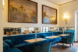 a dining room with blue couches and paintings on the wall at Hotel Vannucci in Citt&agrave; della Pieve