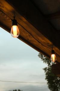 a couple of lights hanging from a wooden ceiling at Tóvidéki Kisház Nyírjes in Nyírjespuszta