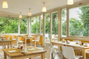 un restaurant avec des tables et des chaises en bois ainsi que des fenêtres dans l'établissement Eurogarden Hotel, à Rome