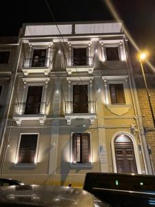 a white building with windows on a street at night at Al Castello Luxury B&B in Reggio Calabria