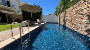 a swimming pool with an umbrella next to a building at Alto da Ria 37 in Alvor