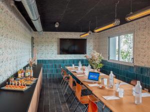 a dining room with long tables and a flat screen tv at Eklo Paris Roissy CDG Airport in Roissy-en-France