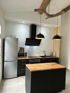cocina con nevera blanca y armarios negros en Au cœur des Caladons, en Lunel 7 fotos más