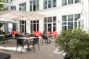 an outdoor patio with tables and chairs and umbrellas at Adina Apartment Hotel Berlin Checkpoint Charlie in Berlin