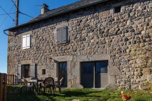 a stone house with chairs and a table in front of it at Gîte Gîtes de France 6/7 personnes à Baboyères in Nasbinals